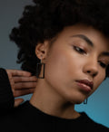 a model wearing minimalist rectangular black powder coated drop earrings from the KONZUK Artus collection