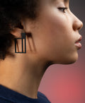 a woman wearing  black powder coated stainless steel geometric earrings from the Artus collection