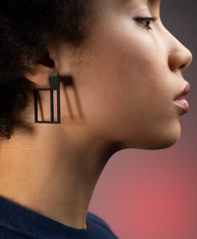 a woman wearing  black powder coated stainless steel geometric earrings from the Artus collection