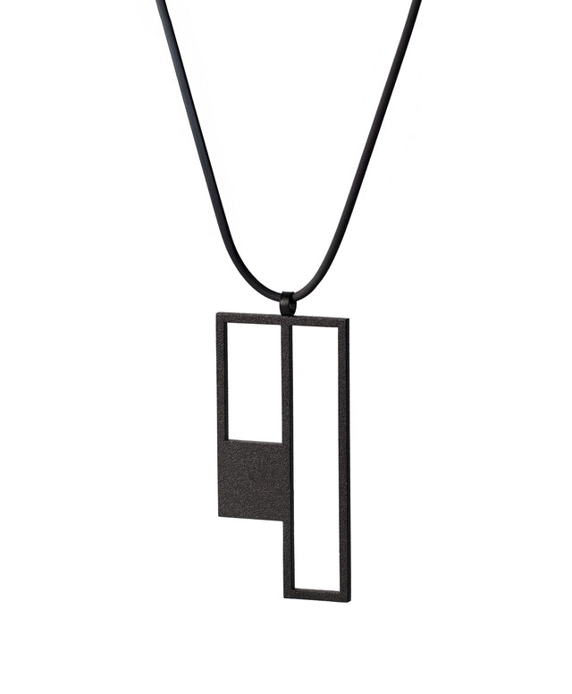 side view of a Black geometric pendant on a black cord against a white background from the KONZUK Artus Ratio collection
