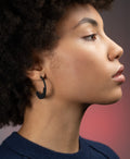 sculptural statement hoop earrings from the KONZUK Artus collection on a model