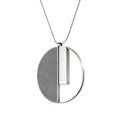 Georg necklace with circular stainless steel and natural concrete pendant, paying homage to Bauhaus legacy. Concrete and stainless steel reflect innovation.