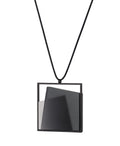 The Astrid necklace in ash grey takes its name from Old Norse, meaning “divinely beautiful,” a reflection of its quiet, sculptural presence. Within the square frame, concrete intersects with resin in a deliberate composition that reveals depth and movement. The meeting of materials creates subtle shifts in tone and surface, drawing the eye to the balance between precision and softness.