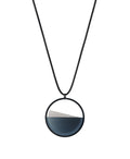The Clara Small necklace in cerulean blue resin captures the essence of clarity in a refined, understated form. Named from the Latin clarus, meaning “bright” or “clear,” it reveals a quiet balance between resin and concrete. Within the circular frame, the concrete emerges gently from the resin’s surface, creating a soft meeting of tone and texture. 