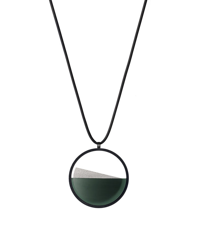 The Clara Small necklace in Cypress green resin captures the essence of clarity in a refined, understated form. Named from the Latin clarus, meaning “bright” or “clear,” it reveals a quiet balance between resin and concrete. Within the circular frame, the concrete emerges gently from the resin’s surface, creating a soft meeting of tone and texture. Subtle and luminous, the Clara Small necklace offers a delicate expression of modern minimalism.