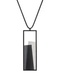 The Eira necklace in Ash grey brings together concrete and resin in a seamless composition that highlights material depth and subtle tone. Within the black rectangular frame, the concrete appears softly suspended in resin, giving the piece a quiet sense of balance and dimension. The surface catches light in a gentle, diffused way, creating an effect that feels both grounded and luminous. The Eira necklace offers a refined expression of modern minimalism.