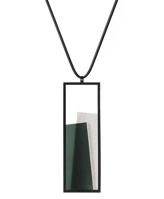 The Eira necklace brings together concrete and resin in a seamless composition that highlights material depth and subtle tone. Within the black rectangular frame, the concrete appears softly suspended in resin, giving the piece a quiet sense of balance and dimension. The surface catches light in a gentle, diffused way, creating an effect that feels both grounded and luminous. The Eira necklace offers a refined expression of modern minimalism.