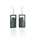 The Elena earrings play with light through a sleek, elongated form. A vertical resin plane reveals a smooth gradient that shifts from light to shadow, bringing subtle movement to the piece. The translucent resin captures and softens light, creating a quiet glow within the structured black frame. Modern and understated, these earrings offer a refined balance of geometry and fluid luminosity. in cypress green
