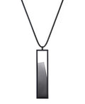 The Lucia necklace in Ash grey resin features a sleek rectangular pendant that emphasizes form and material. A cast resin element rests within a black frame, creating a sense of depth and quiet luminosity. The elongated shape draws the eye, offering a refined balance between structure and softness. Minimal and striking, the Lucia necklace adds a sculptural accent that complements both everyday and statement looks.