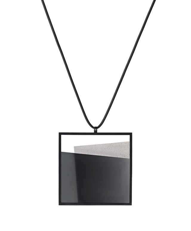 Derived from the Latin  mare, meaning “sea,” the Mara necklace in ash grey evokes depth, stillness, and movement within form. Concrete is cast into resin inside a square frame, where the materials meet in a smooth, fluid line. The surface reflects light with quiet subtlety, creating the sense of horizon and depth. The Mara necklace embodies balance and serenity through modern, sculptural design.
