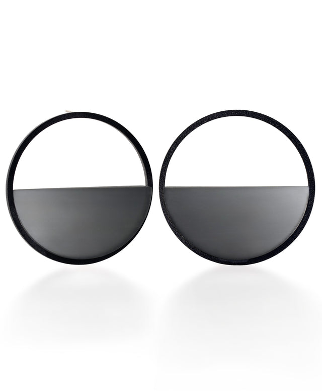 The Sola earrings feature a bold circular form that highlights the depth and tone of cast ash gray resin. Larger in scale, they create a sculptural statement while maintaining a sense of balance and simplicity. The smooth surface holds a quiet luminosity that contrasts beautifully with the dark frame, giving the design a modern yet understated presence.