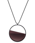 The Vestra necklace in Cognac resin embodies balance and quiet strength. Its name, derived from the Latin vestra, meaning “yours,” speaks to a personal connection between wearer and form. Within the circular frame, concrete is cast into resin revealing a smooth plane of depth and tone, reflecting light in a soft, fluid way. The composition feels calm and grounded, offering a sculptural presence that becomes uniquely individual when worn.