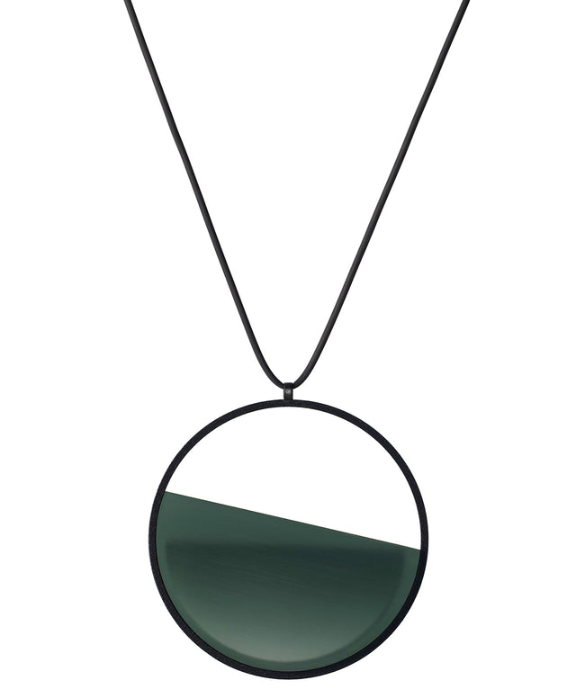 The Vestra necklace in Cypress green resin embodies balance and quiet strength. Its name, derived from the Latin vestra, meaning “yours,” speaks to a personal connection between wearer and form. Within the circular frame, concrete is cast into resin revealing a smooth plane of depth and tone, reflecting light in a soft, fluid way. The composition feels calm and grounded, offering a sculptural presence that becomes uniquely individual when worn.