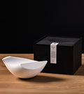 White large (Mère) Oiseau perched next to custom box gift packaging.