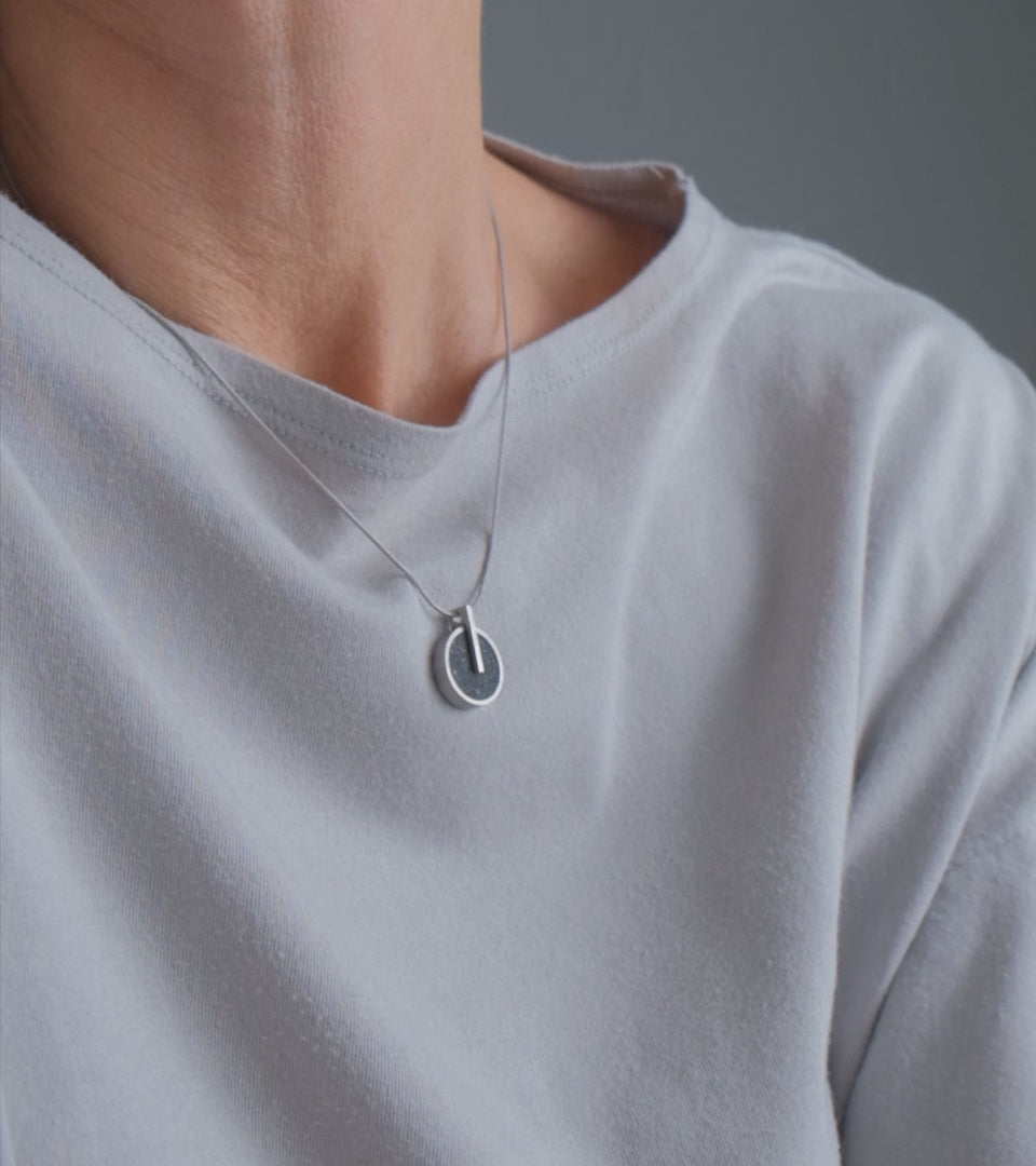 Video of model wearing Memento Eternal pendent with diamond dust concrete set into small circular stainless steel design.