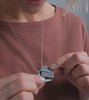 Video of model wearing Memento Mindful locket set with concrete into a round stainless framework.