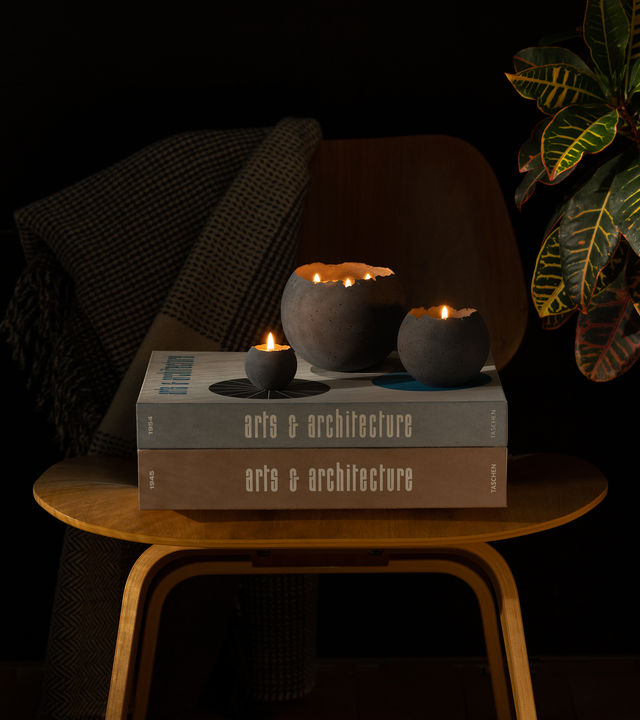Concrete candles in various sizes sit on top of Taschen's Arts & Architecture coffee table books while set on Eames molded plywood chair.