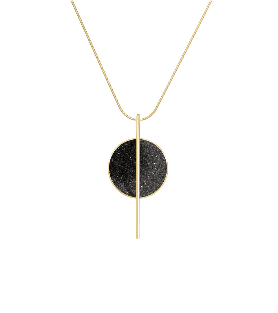 The Linnea 14k necklace features black concrete and the sparkle of embedded diamond dust set into a 14 karat gold dome intersected by a steel post suspended by a gold cable.
