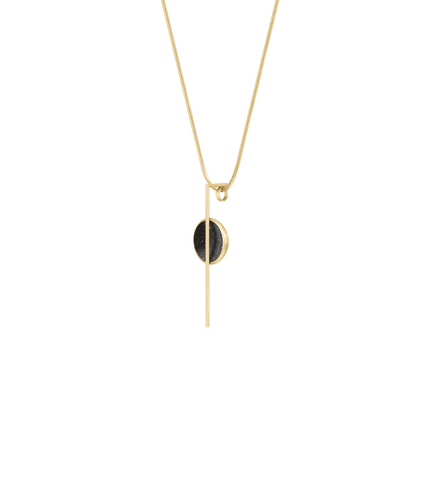 The Linnea Minor 14k necklace features black concrete and the sparkle of embedded diamond dust set into a 14 karat gold dome intersected by a steel post and suspended by a gold cable.