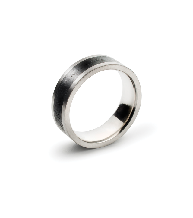 Quarter view of a KONZUK men's wedding ring with black concrete set into a brushed stainless steel minimalist design.