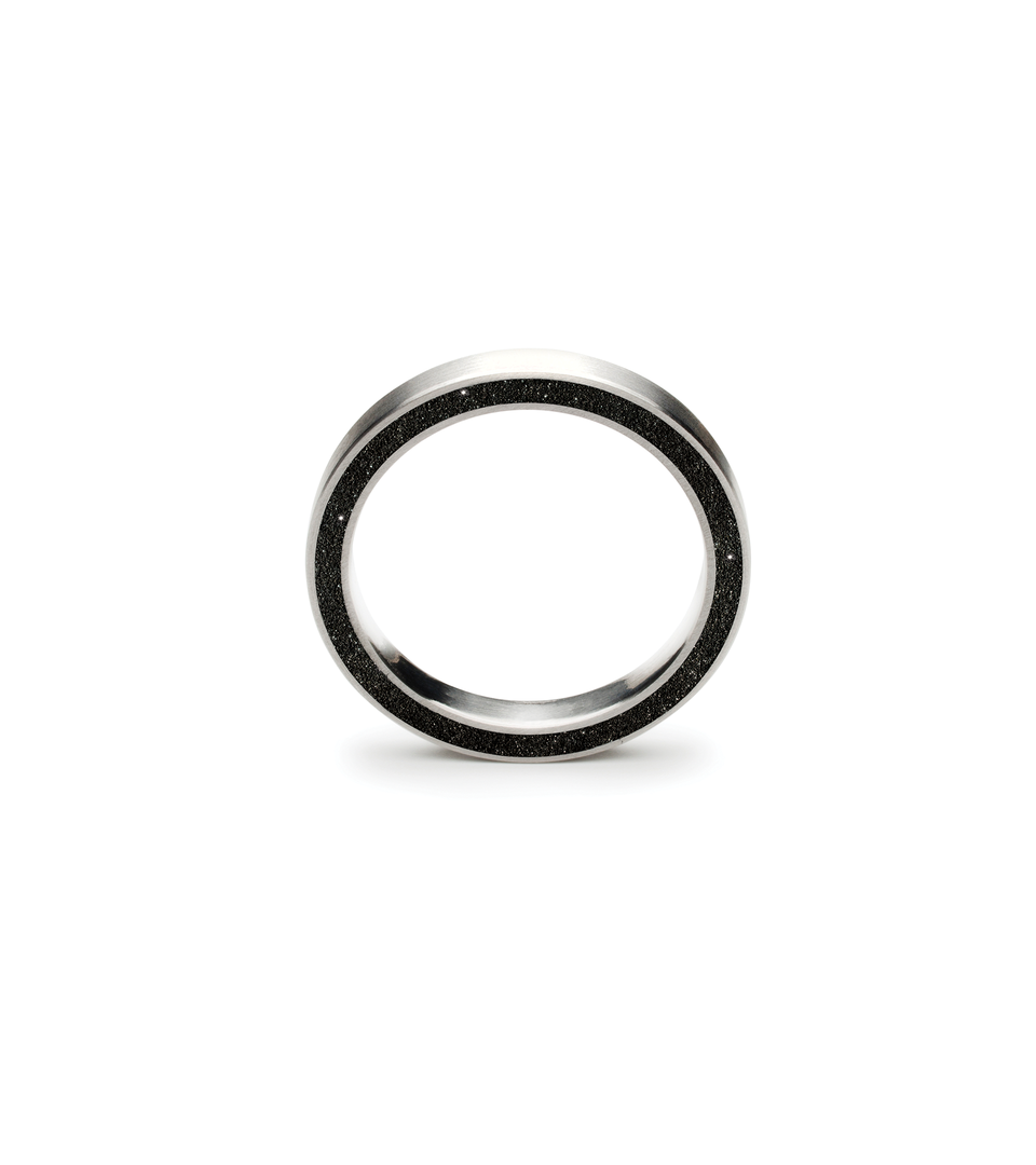 Diamond dust encrusted black concrete is set into the side of a thinner modern ring.