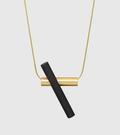 Unity necklace with 14k solid gold chain with a 14k gold tube. This is intersected by a black concrete cylinder.