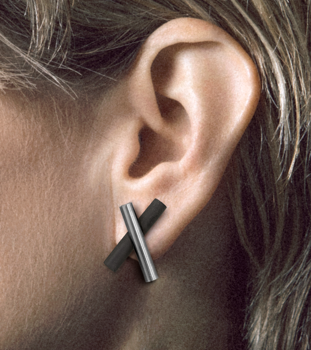 Model wears studs distinctly characterized by intersecting small stainless steel and concrete cylinders.