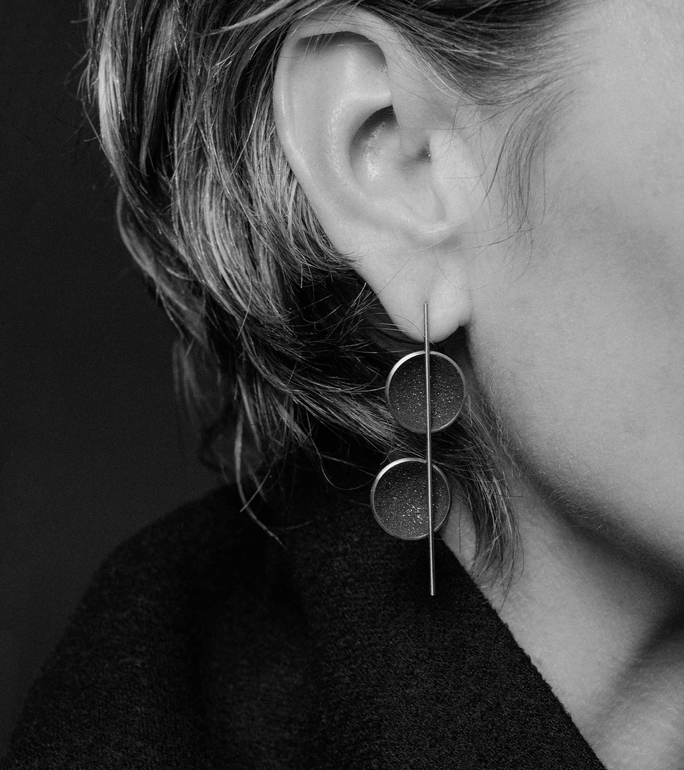 Bauhaus like designed earrings featuring concrete and diamond dust set into two stainless steel domes suspended architecturally from a small steel post.