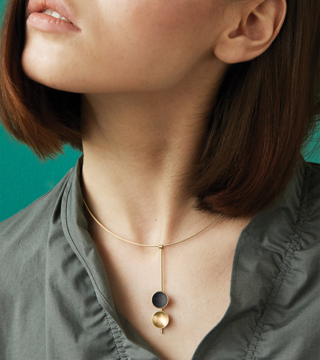 The Freya Minor modern necklace features two double 14 karat gold domes, one lined with diamond dust infused black concrete both architecturally supported an elegant hanging 14k gold post.