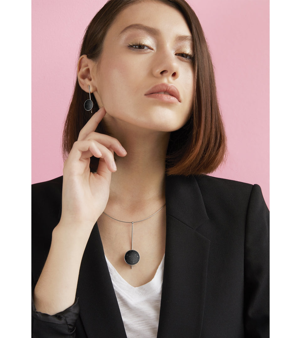Bauhaus inspired Inspira necklace sparkle with diamond dust and black concrete set into a stainless steel dome architecturally suspended on top of a minimalist steel post. 