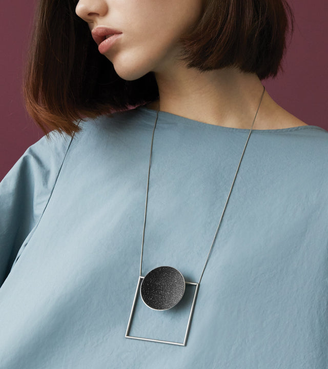 Contemporary necklace combines the geometry of a large stainless steel dome lined with the sparkle of diamond dust encrusted concrete suspended onto a minimalist steel square frame.