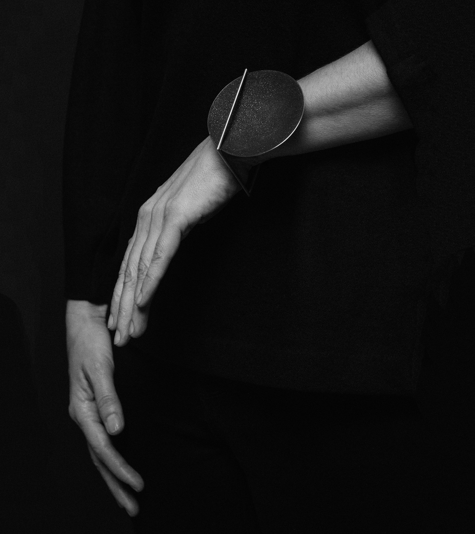 The minimalist Frama Max bracelet sparkles with diamond dust and black concrete set into a larger stainless steel dome architecturally suspended inside a minimalist steel square frame.