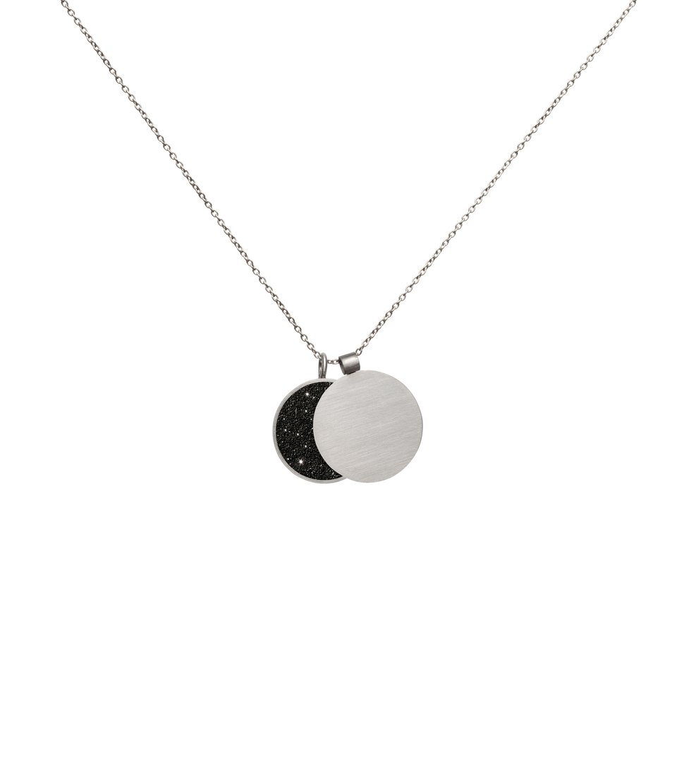 This minimalist overlapping double pendant in concrete, diamond dust and stainless steel hangs centred and shapes the phases of the moon depending on how the piece hangs. 