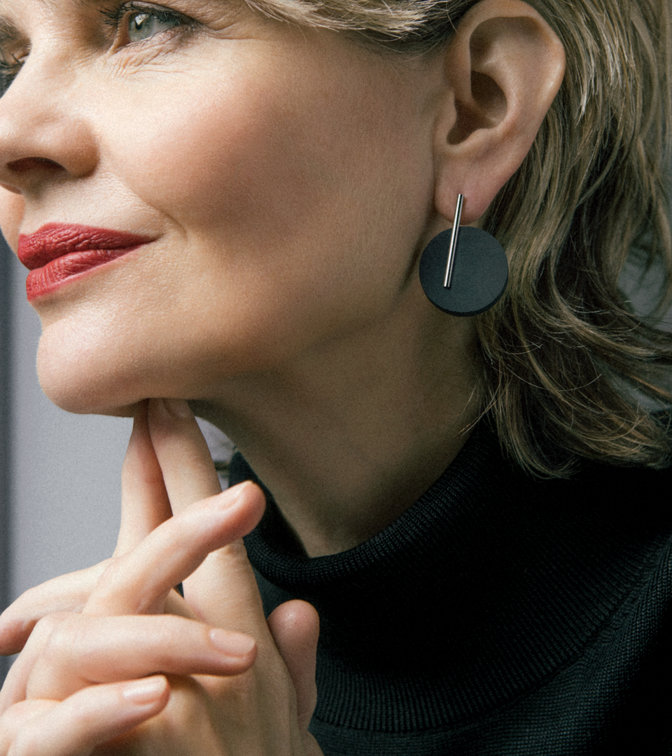 Model wears larger black music-note-like concrete earring by Konzuk.