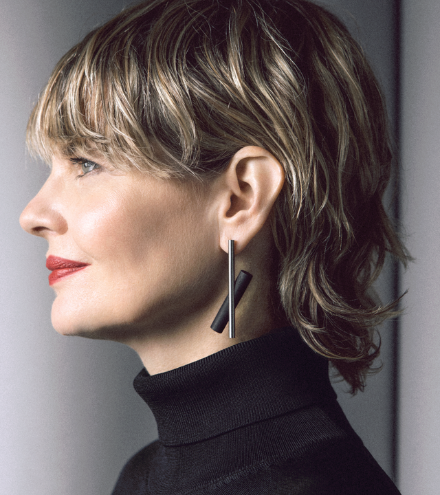 The modern design of the Unity x earrings (large) is highlighted by a natural or black concrete cylinder juxtaposed behind a brushed stainless steel rod.