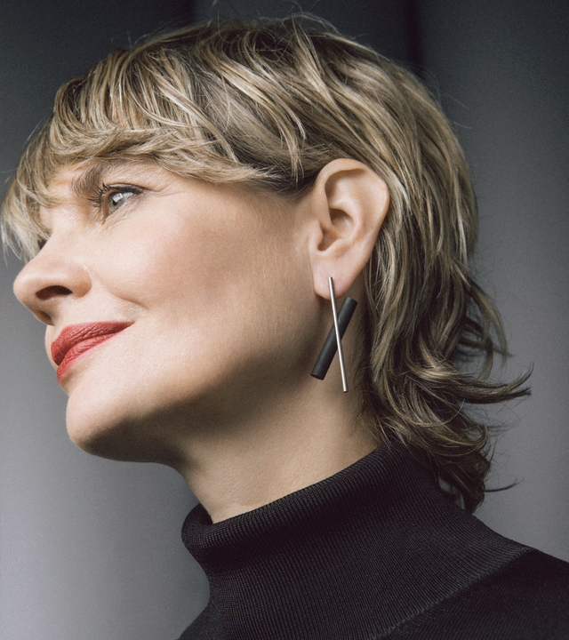 The modern design of the Unity x earrings (small) is highlighted by a natural or black concrete cylinder juxtaposed behind a thin brushed stainless steel rod.