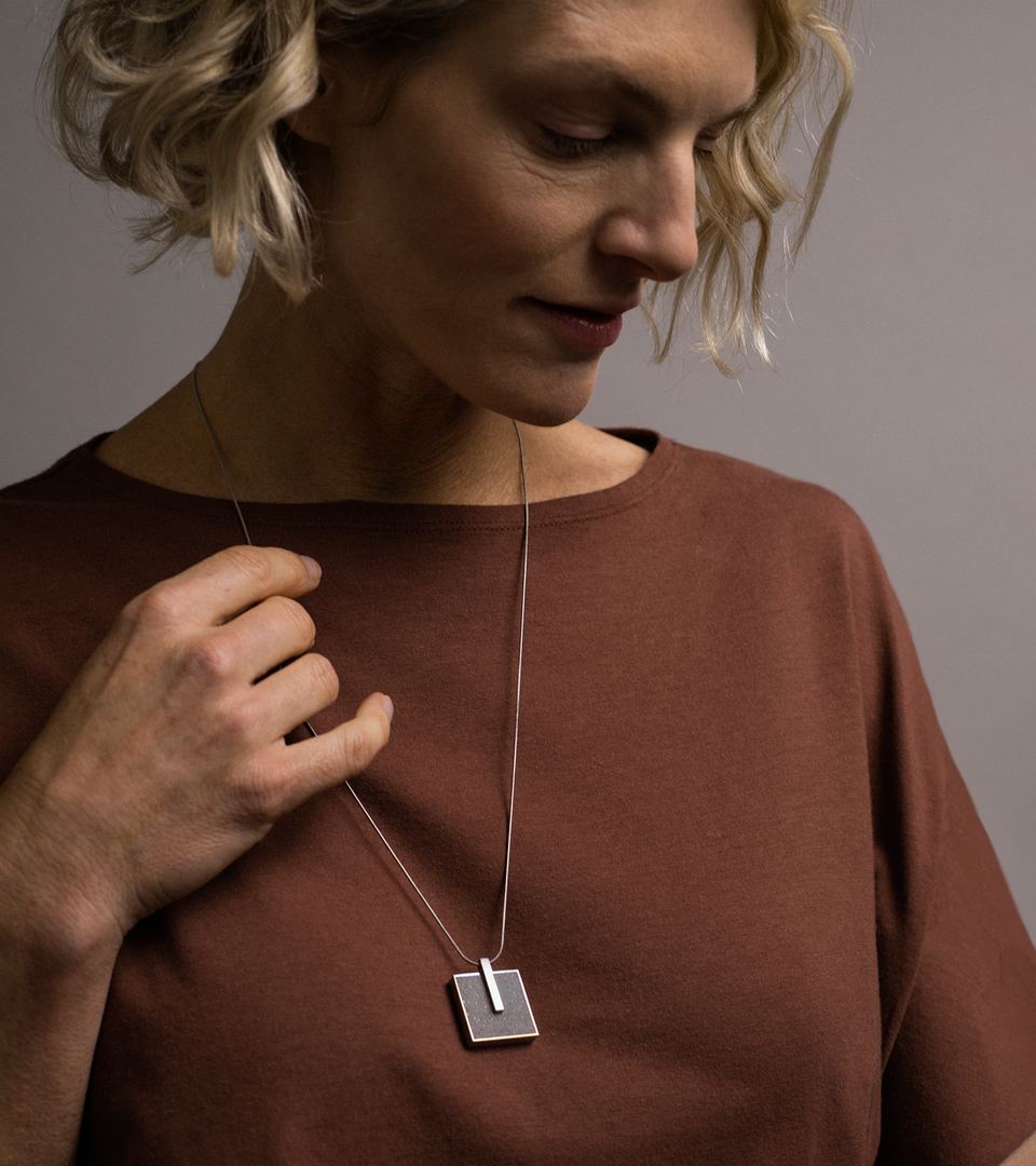 Model wears square stainless steel locket set with natural concrete.